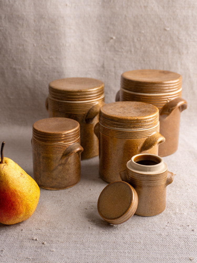 Set of five vintage French Digoin Grespots stoneware pots, various sizes, on beige fabric with yellow pear.