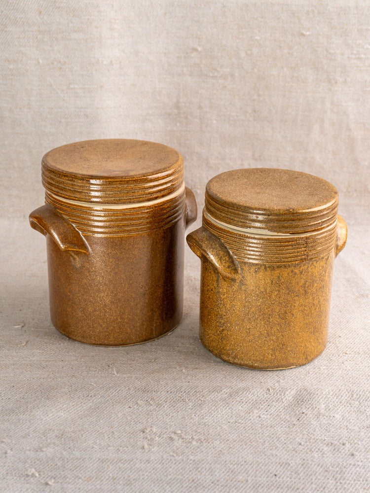 Set of five vintage French Digoin stoneware pots with classic rustic shapes on fabric backdrop.