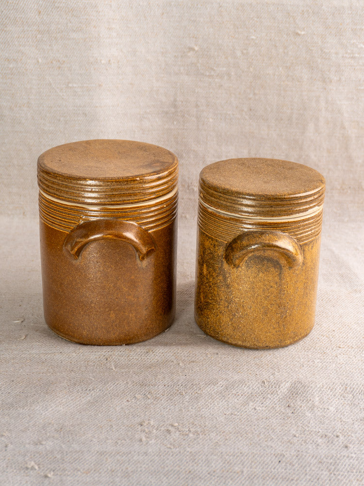 Pair of vintage French Digoin stoneware pots with rustic finish and horizontal ridges on beige fabric.