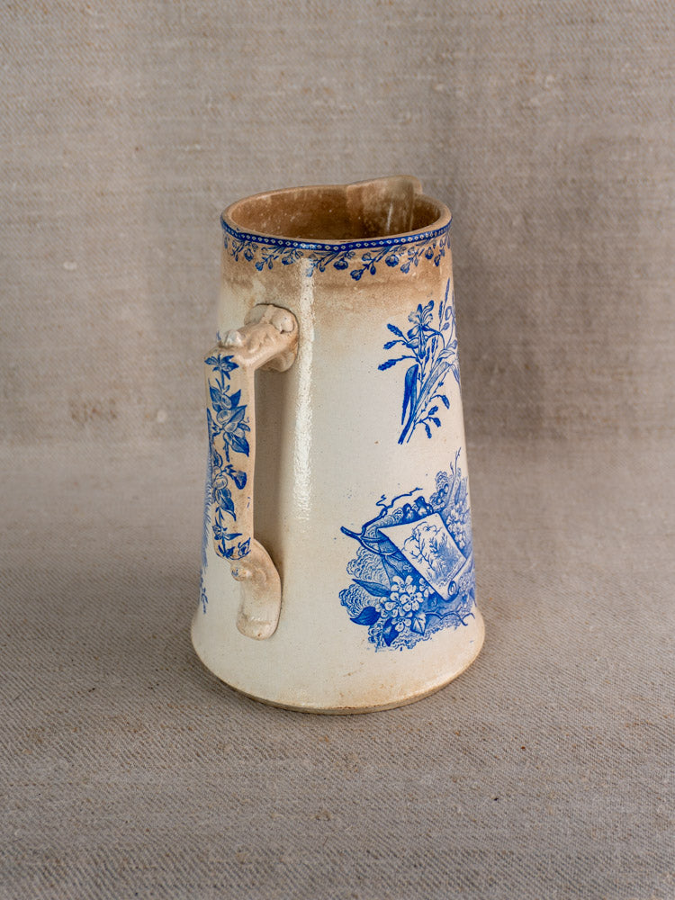 Antique French Fenal Frères ceramic pichet with Pexonne Oiseaux blue floral pattern, on beige fabric.