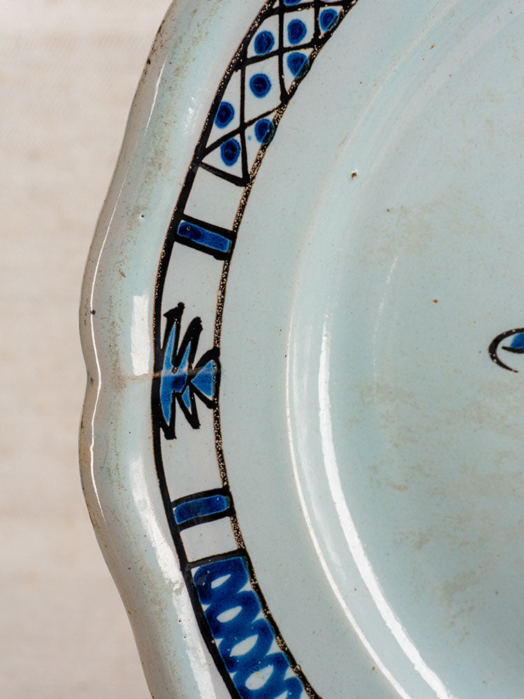 Antique French faience plate, Cul Noir, 19th century, scalloped edge with Rouen blue and black geometric rim pattern.