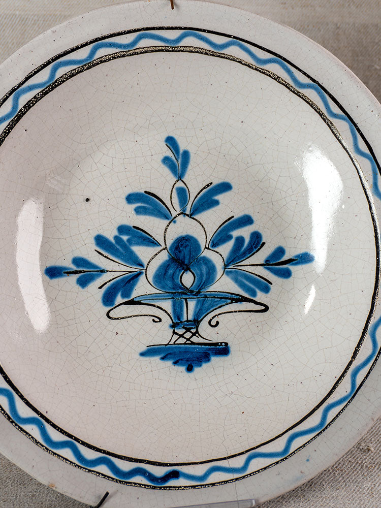 Antique French faience Cul Noir charger with hand-painted blue floral basket, blue and black borders, cracked glaze.