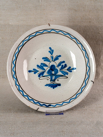 Antique French Cul Noir faience charger, late 18th century, blue Panier Fleuri motif, cracks, metal repairs; neutral fabric backdrop.