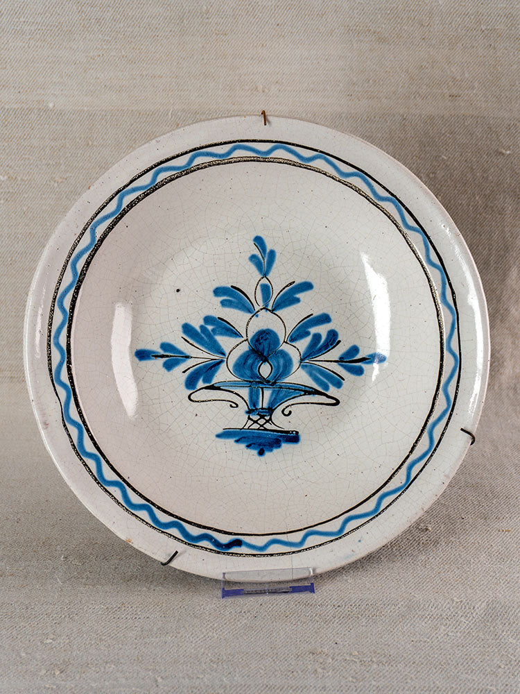 Antique French Cul Noir faience charger, late 18th century, hand-painted Panier Fleuri, double blue border, on fabric backdrop.