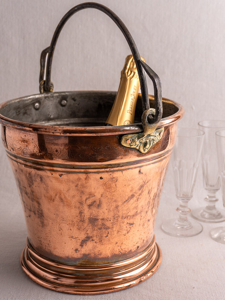 Late 19th-century French copper bucket with engraved band and metal handle, slightly tarnished on a gray background.