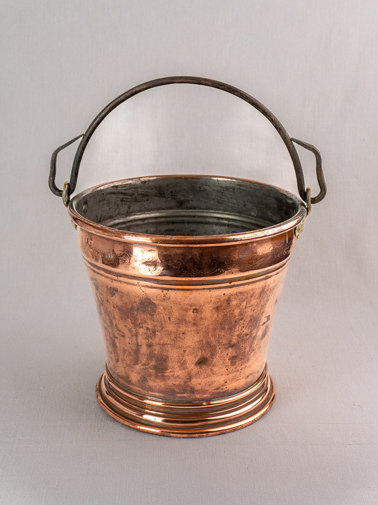 Late 19th-century French copper bucket with engraved band and metal handle, slightly tarnished on a gray background.