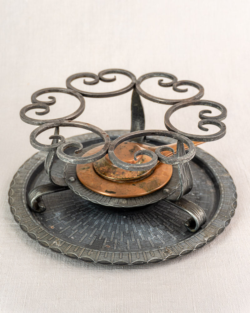 Antique French copper fondue set with hammered pot, ornate iron stand, swirling accents, and central candle holder.