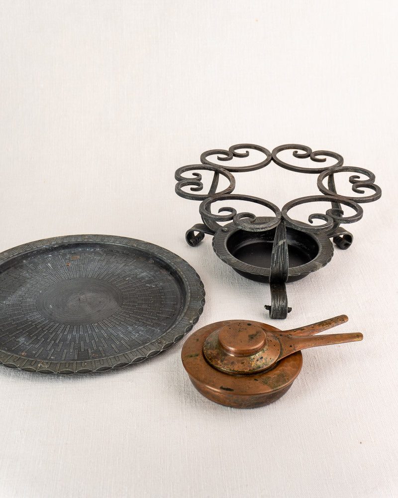 Antique French copper fondue set with hammered pot, iron warmer stand, matching bowls, and two spoons on a light surface.