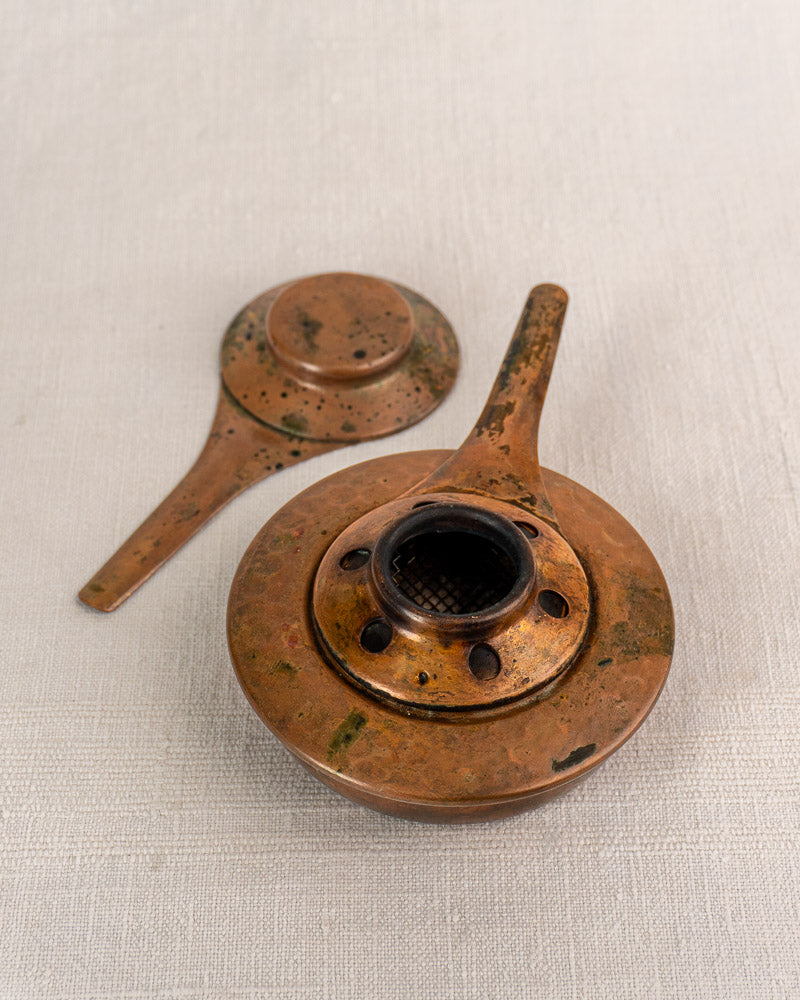 Pair of vintage brass tea strainers with handles on textured fabric, showcasing Old World elegance and patina.