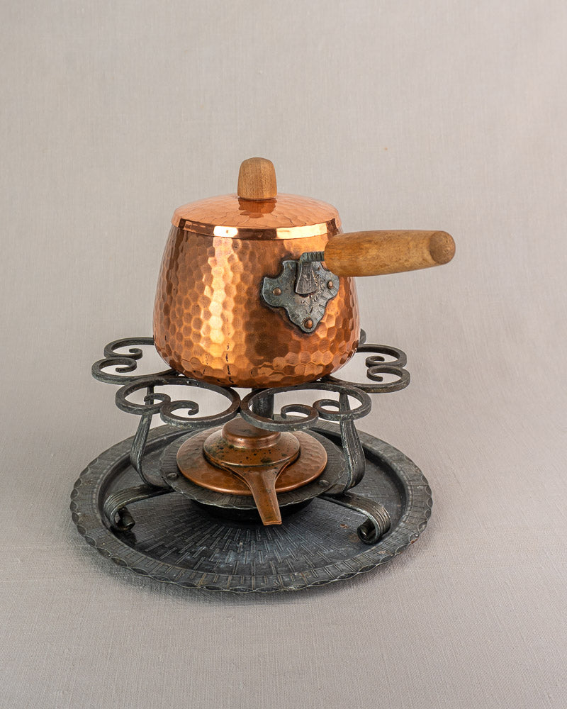 Antique French hammered copper fondue set with wooden handle, lid, and iron warmer stand.