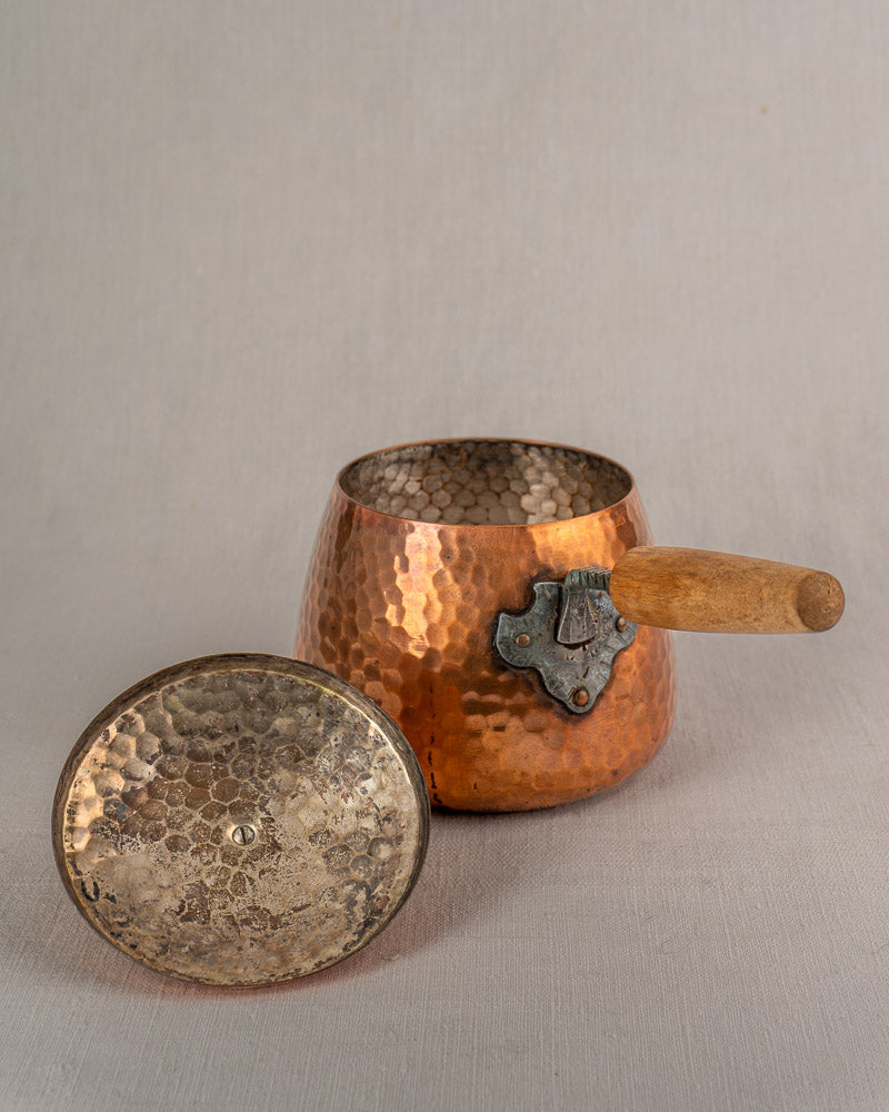 Antique French copper fondue set with hammered pot, wooden handle, ornate fittings, and iron warmer stand on neutral background.