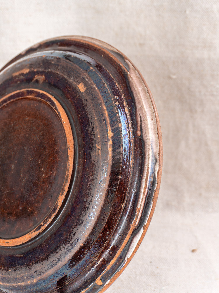 Underside of late 19th-century French faience plate with rooster design, textured rings, and matte finish.