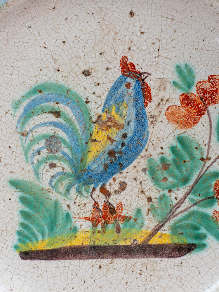 Antique French faience plate, late 19th century, hand-painted rooster and red flowers, rustic wear and brown spots.