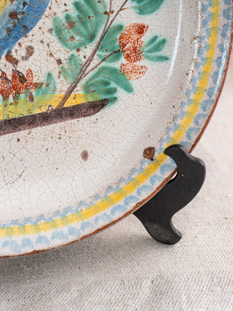 Antique French faience plate, late 19th century, hand-painted rooster, cracked glaze, blue-yellow rim, on black stand.