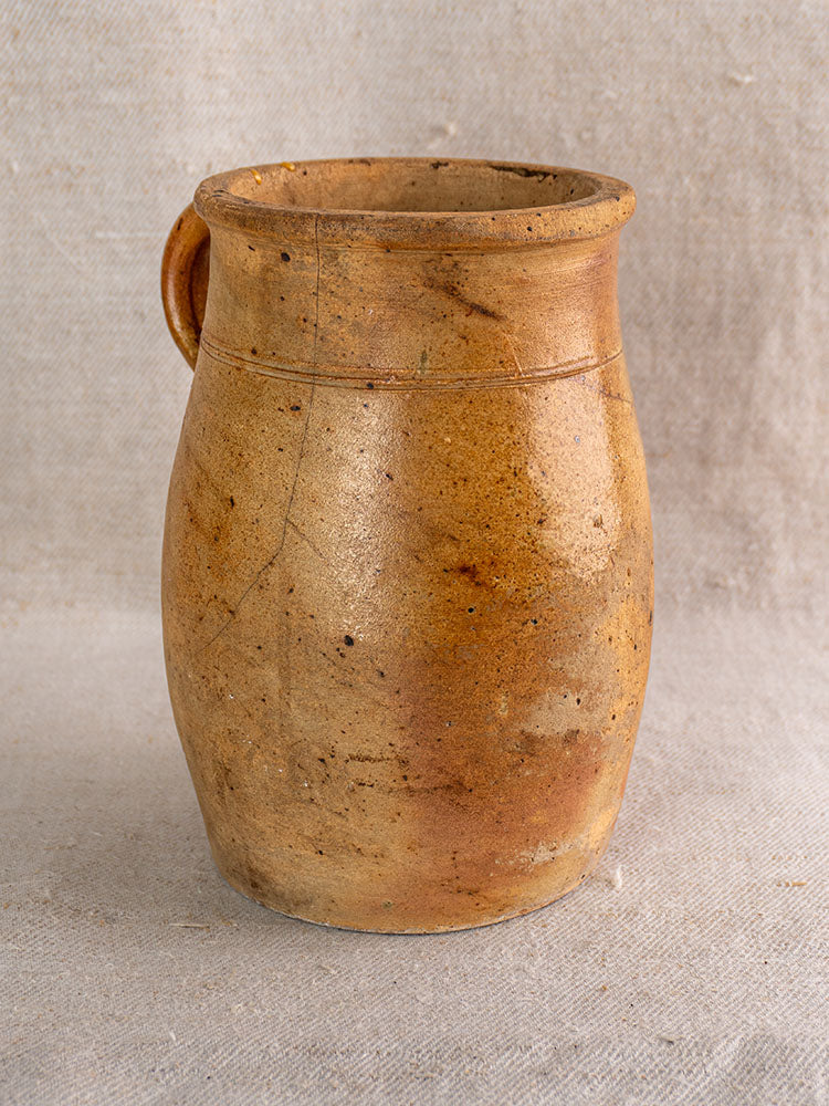 Antique French stoneware pitcher, early 19th century, rustic brown salt-glazed finish, handmade details on neutral textured fabric.
