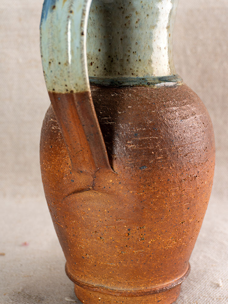 Antique French stoneware pitcher from La Borne with reddish-brown texture and blue ash celadon glazed handle and neck.