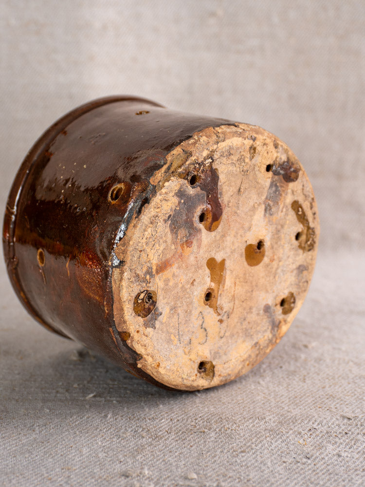 Pair of 19th century French ceramic cheese strainers, brown glazed, upside down showing unglazed bases and drainage holes on fabric.