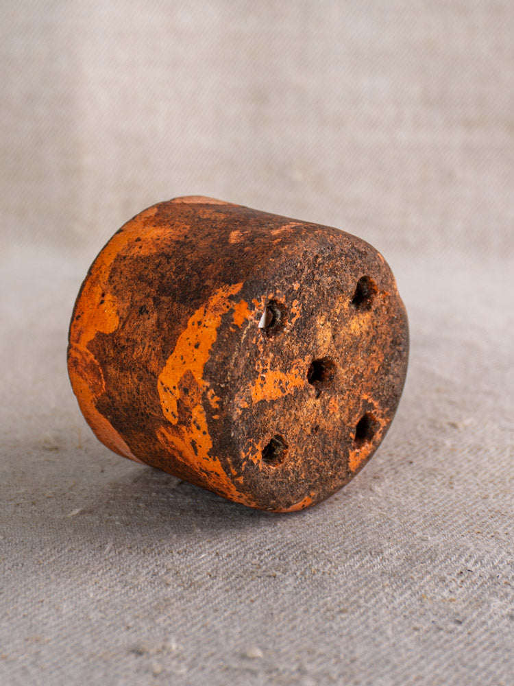 Pair of 19th century French ceramic cheese strainers with peeling orange paint and five round holes on gray fabric.