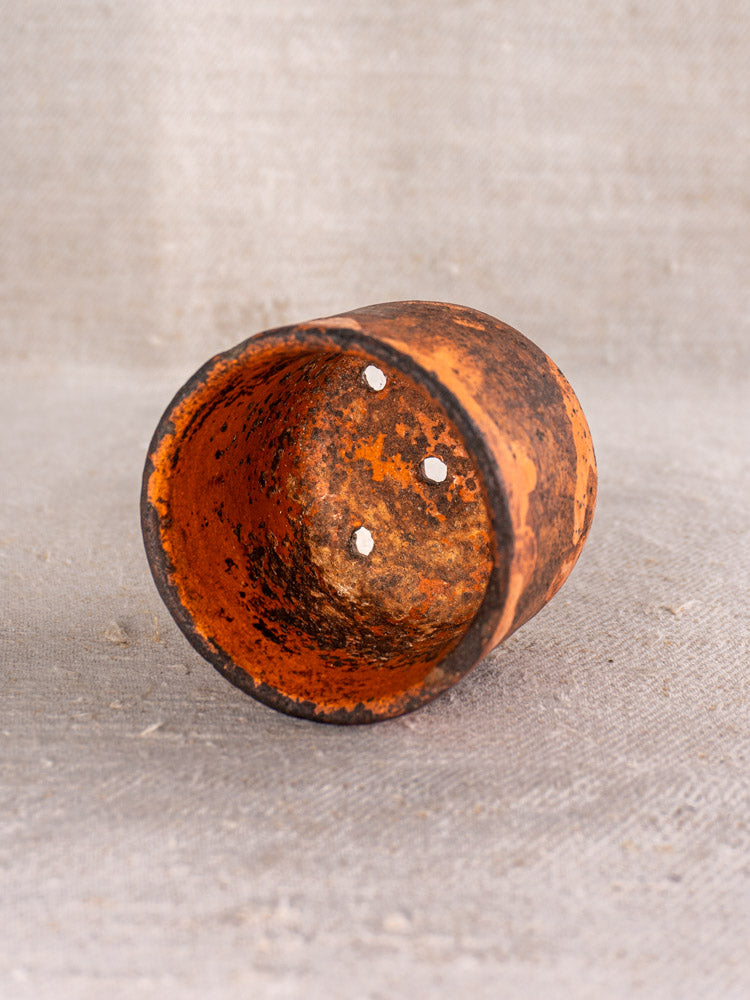 Pair of 19th century French ceramic cheese strainers in rustic orange, three drainage holes, on textured beige surface.