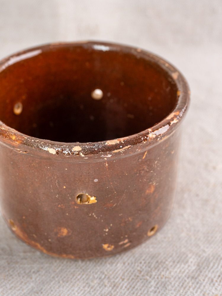 Pair of 19th century French ceramic cheese strainers with small holes and rim wear on textured fabric surface.