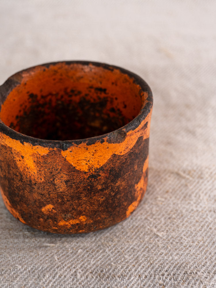 Pair of 19th century French ceramic cheese strainers with orange terracotta glaze and black markings on textured beige fabric.
