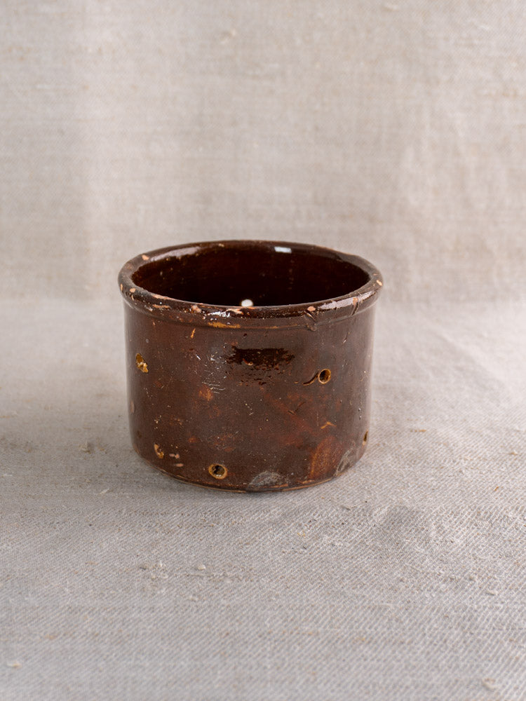 Pair of small 19th-century French ceramic cheese strainers with glossy brown glaze and side holes on light fabric.