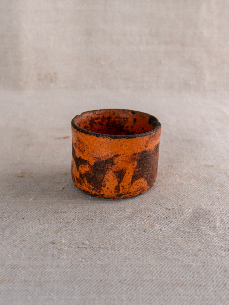 Pair of 19th-century French ceramic cheese strainers with orange and dark brown textures on light woven fabric.