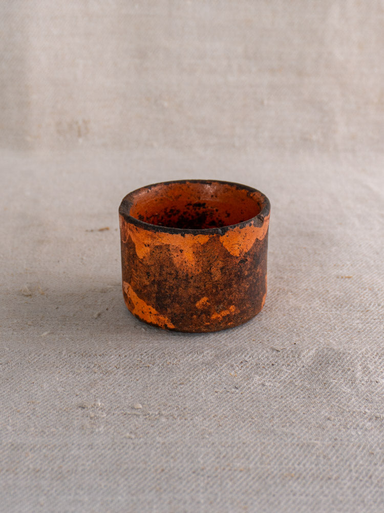Pair of 19th century French ceramic cheese strainers with mottled orange and brown glaze on woven fabric background.
