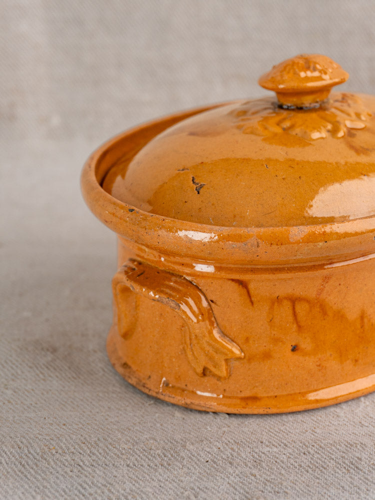Antique French terrine in mustard ochre glaze with lid and handle, subtle embossed patterns, farmhouse style.
