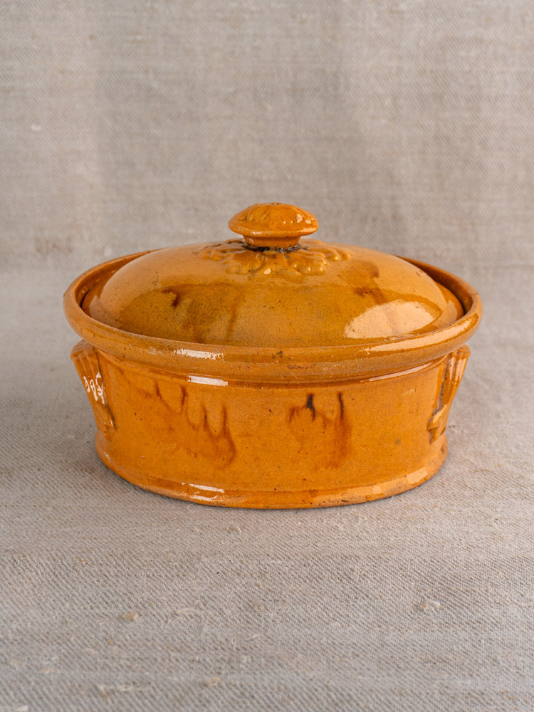 Antique French terrine with mustard ochre glaze, Vendeuvre faïenceries, late 19th–early 20th c., on neutral textured surface.