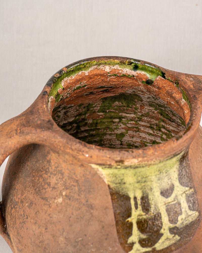 Antique French glazed terracotta vinaigrier showing rustic brown ceramic with green and cream glaze accents.