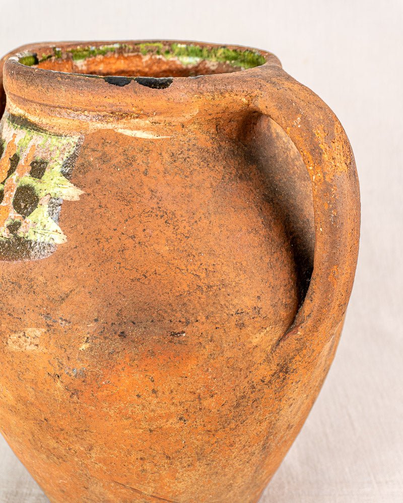 Antique French glazed terracotta vinaigrier with rustic brown clay, large handle, greenish rim accents.