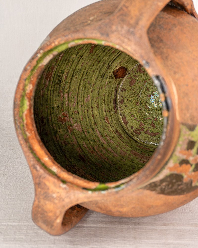 Antique French glazed terracotta vinaigrier with weathered brown exterior and greenish, textured interior.