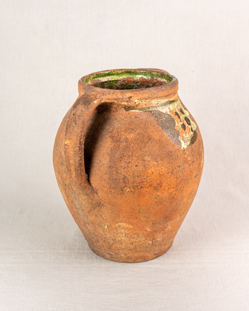 Antique French glazed terracotta vinaigrier, brown body with green glaze accents, on light gray background.