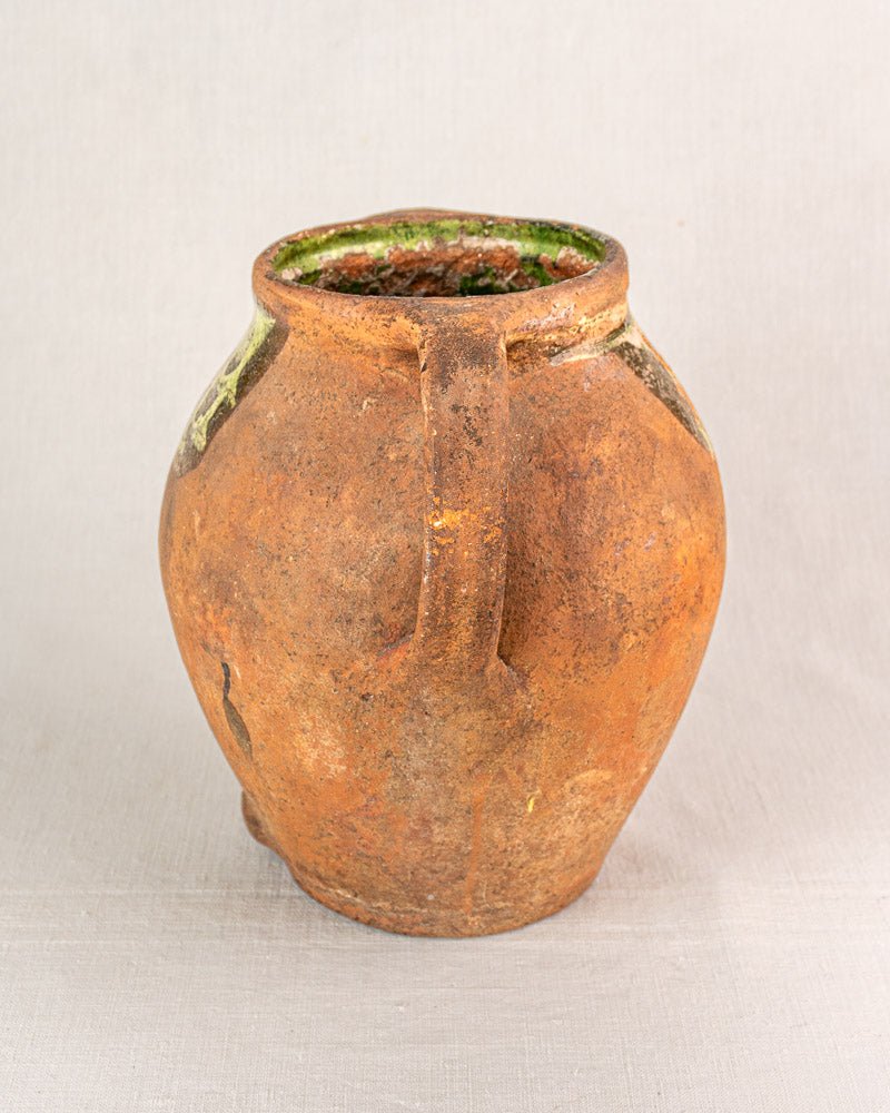 Antique French terracotta vinaigrier with single handle, brown-orange glaze, and green accents near rim.