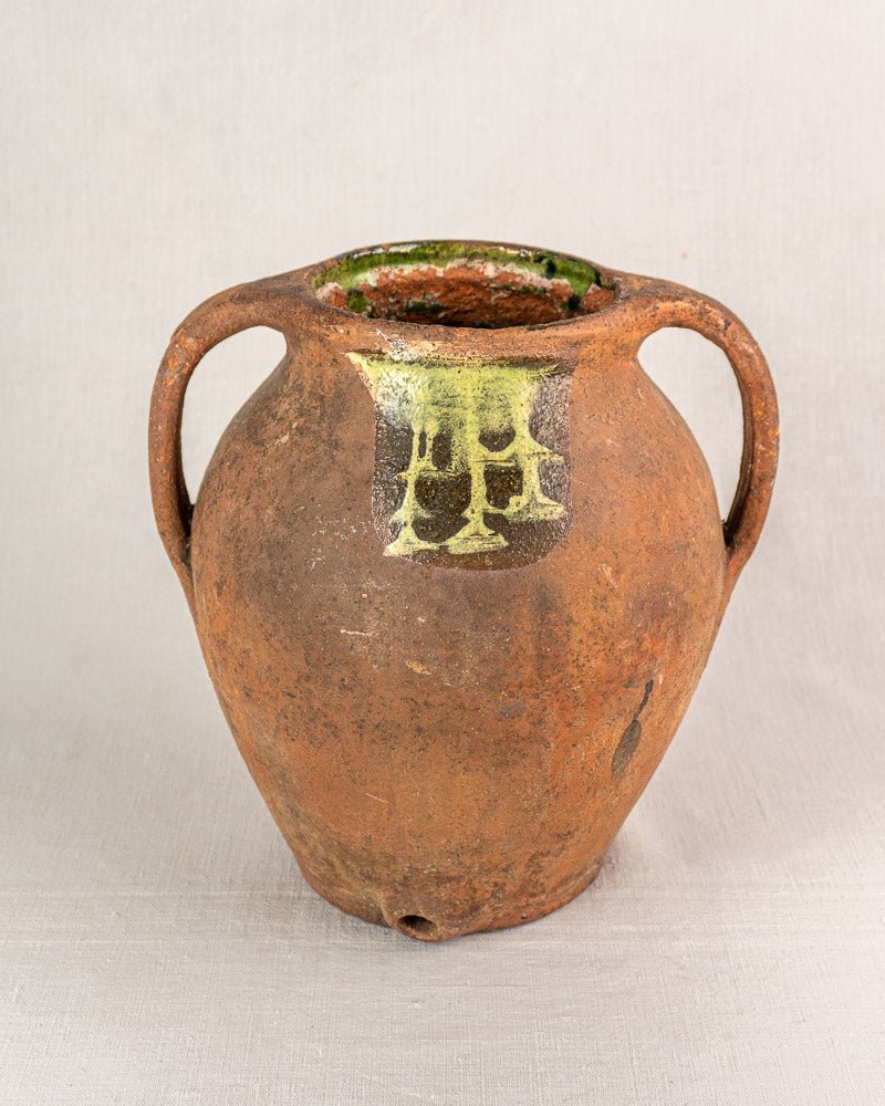 Antique French glazed terracotta vinaigrier with twin handles, green-glazed rim, and yellow-green motif.