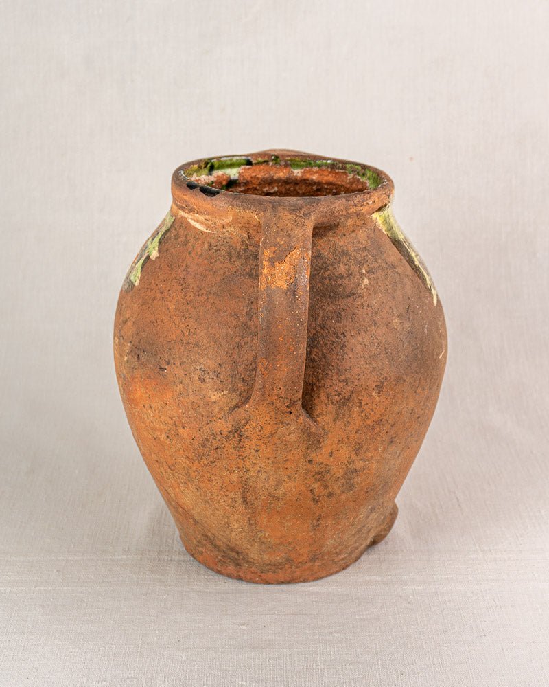 Antique French glazed terracotta vinaigrier, weathered brown with a chipped rim and greenish patina.