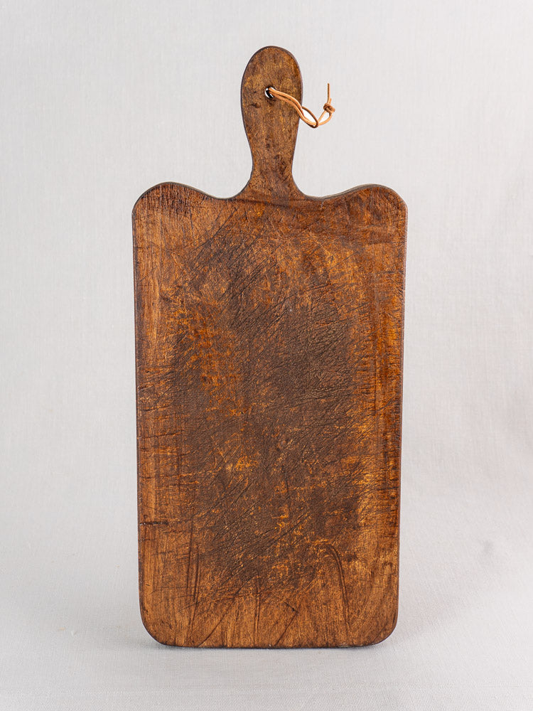 Antique French cutting board with paddle handle, late 19th century, upright with worn surface on light gray background.