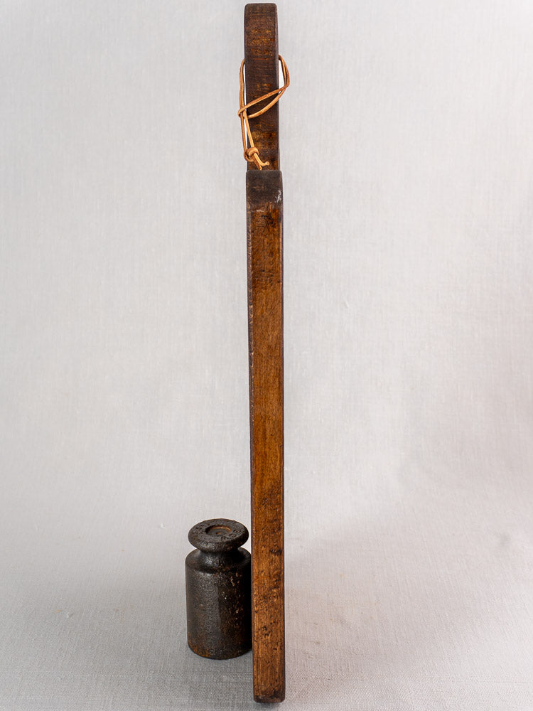 Antique French cutting board with paddle handle, late 19th century, against a neutral textured background.