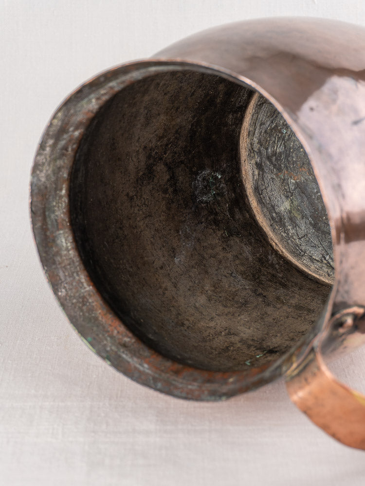 Antique French hammered copper pitcher with dark, uneven patina and visible interior corrosion, late 18th century.
