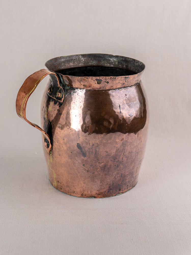 Antique French copper pitcher, late 18th century, hand-hammered with wide mouth, patina, on a neutral backdrop.