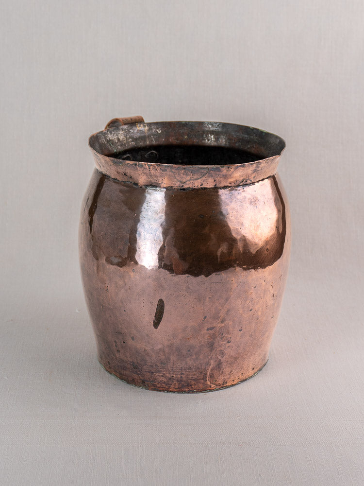 Late 18th century French hammered copper pitcher with flared rim, side handle, and rich patina, set on light-gray background.