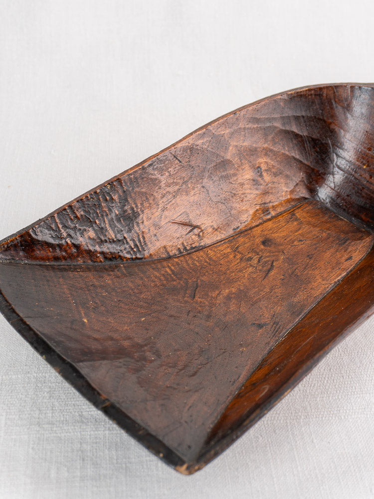 Antique French wooden grain scoop, hand-carved 19th-century piece with visible texture on light fabric backdrop.