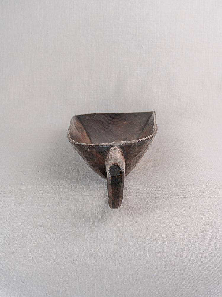 19th-century French hand-carved wooden grain scoop with rounded handle and deep bowl on light gray background.
