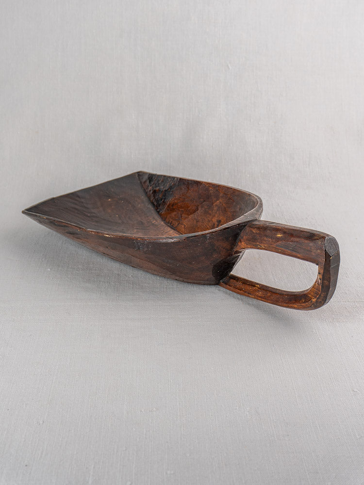 Antique French hand-carved wooden grain scoop with wide flat bowl and rectangular handle on light gray surface.