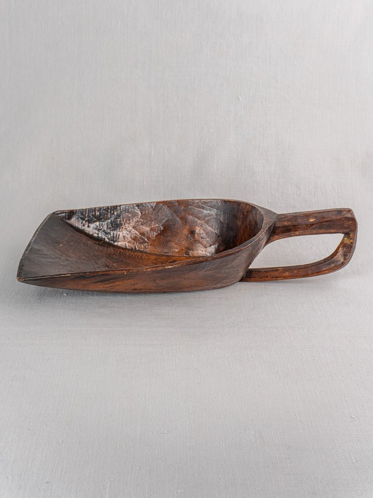 19th-century French hand-carved wooden grain scoop with deep bowl, angled handle, and rich dark finish highlighting natural grain.