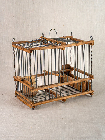 Handmade early 20th-century French folk art bird cage in wood and wire with hinged door, displayed on beige fabric.