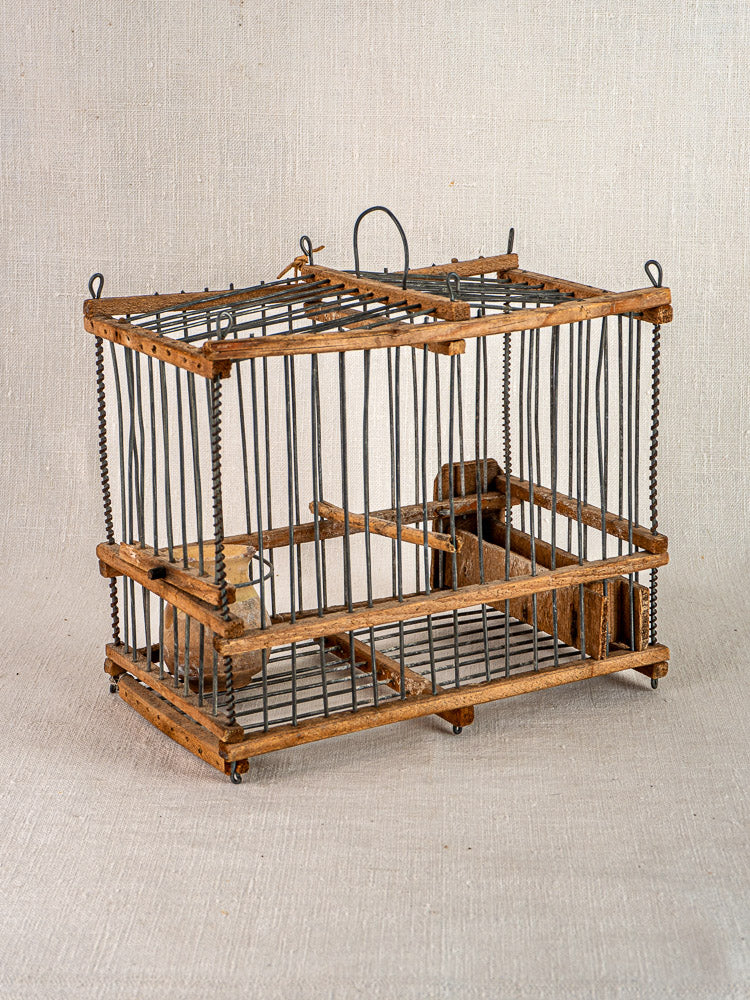 Handmade early 20th-century French folk art bird cage in wood and wire with hinged door, displayed on beige fabric.