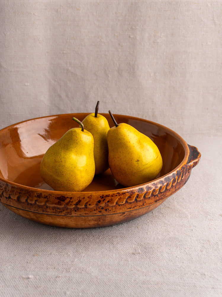 Antique French Vitry-le-François gratin dish in glazed stoneware with decorative edge, yellow pears inside.