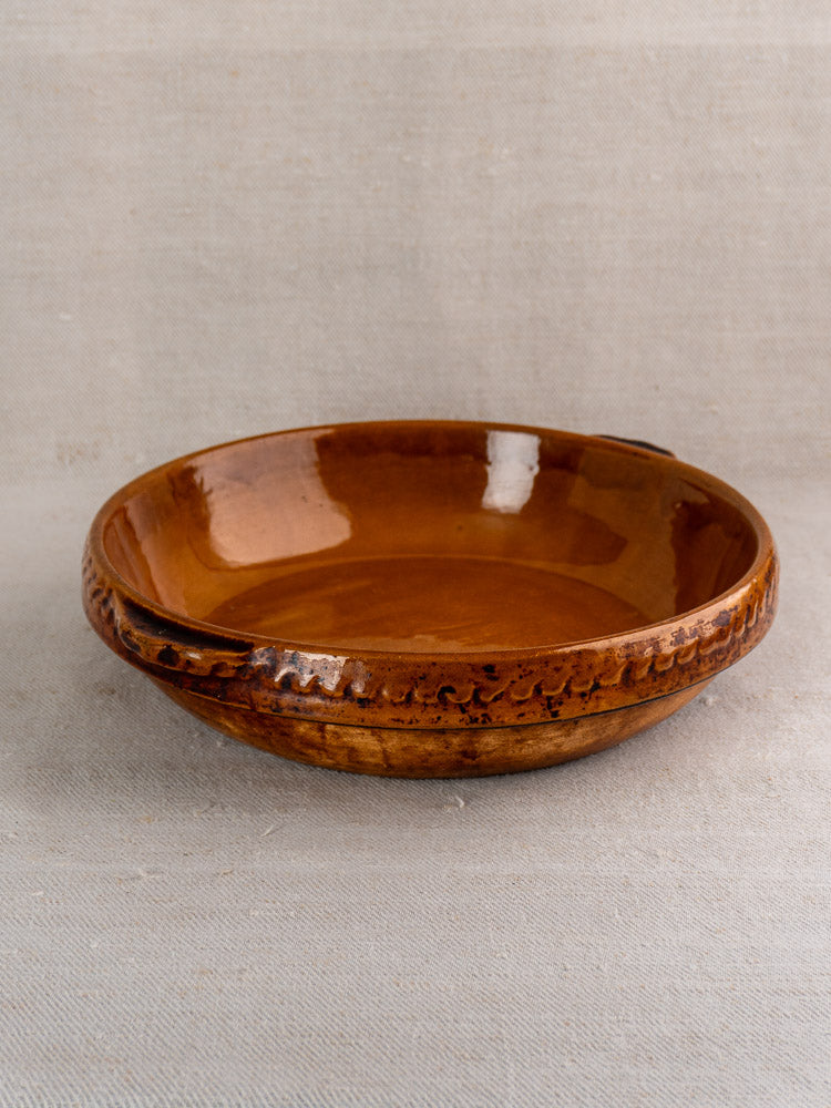 Antique French Vitry-le-François gratin dish in glazed stoneware with glossy brown finish on neutral fabric background.